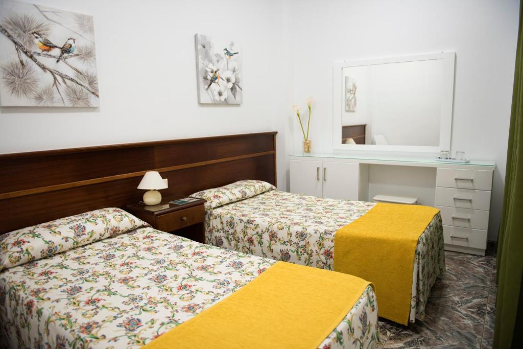 Cette chambre comprend 2 lits et un miroir. dans l'établissement Pension Los Geranios, à Puerto de la Cruz