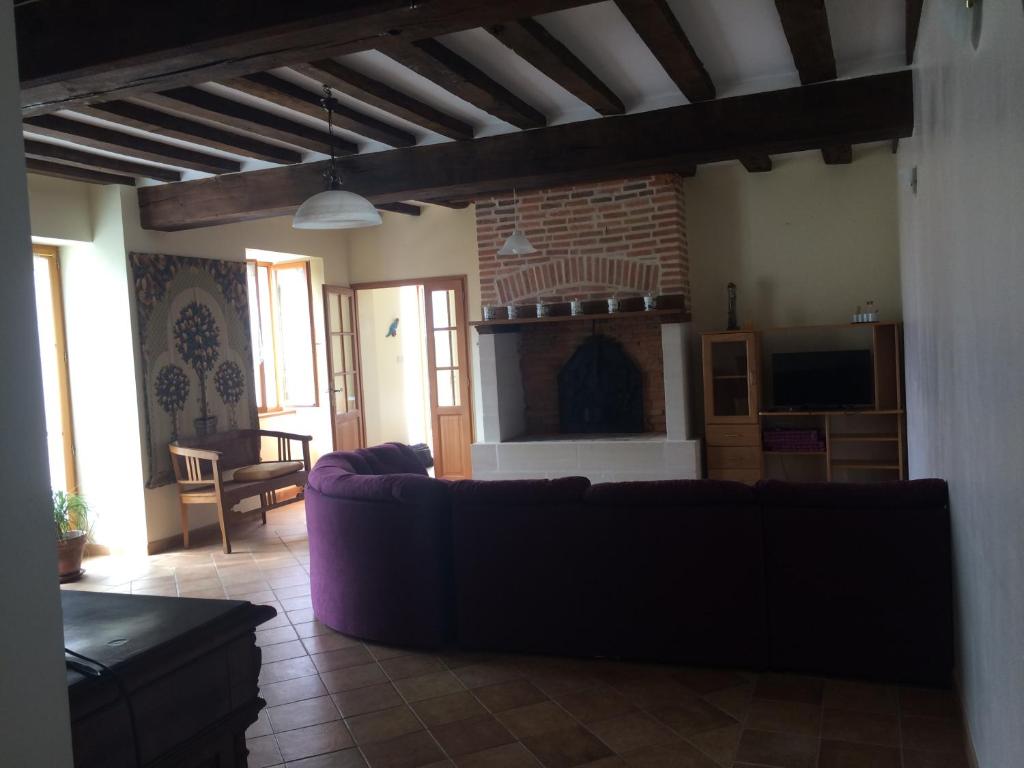 sala de estar con sofá y chimenea en Gite de la Boheraie, en Chemazé