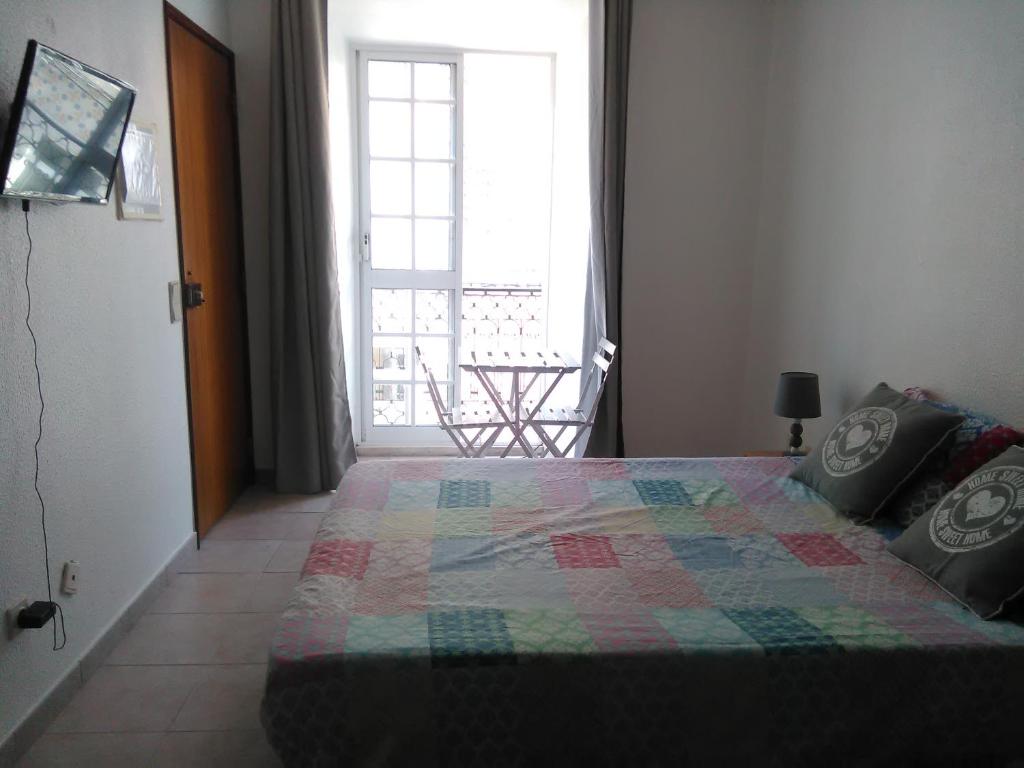 a bedroom with a bed with a quilt on it at Casa Eloy in Setúbal