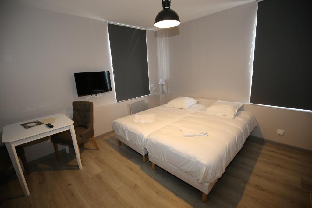 a bedroom with a bed and a table and a tv at L'Hotel De France in Roubaix