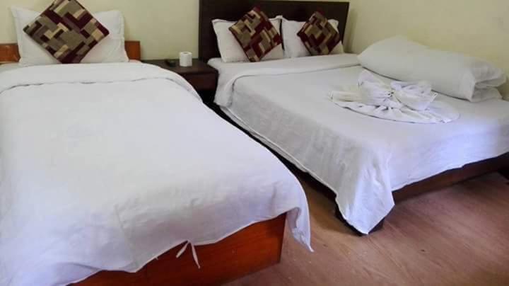 two beds in a room with white sheets at Hotel Sisters Home in Kathmandu