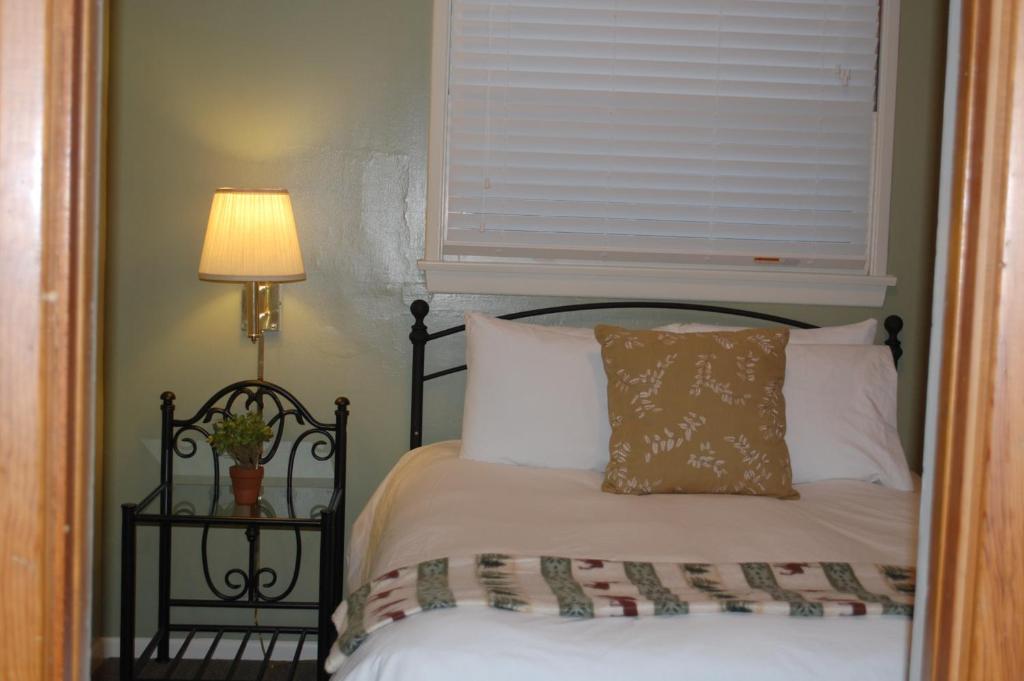 1 dormitorio con 1 cama con ventana y lámpara en Trees Motel, en Bishop