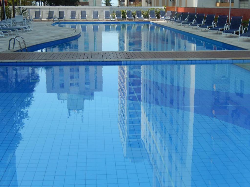 a swimming pool with chairs and blue water at Vista ao Mar & Lazer Total in Guarujá