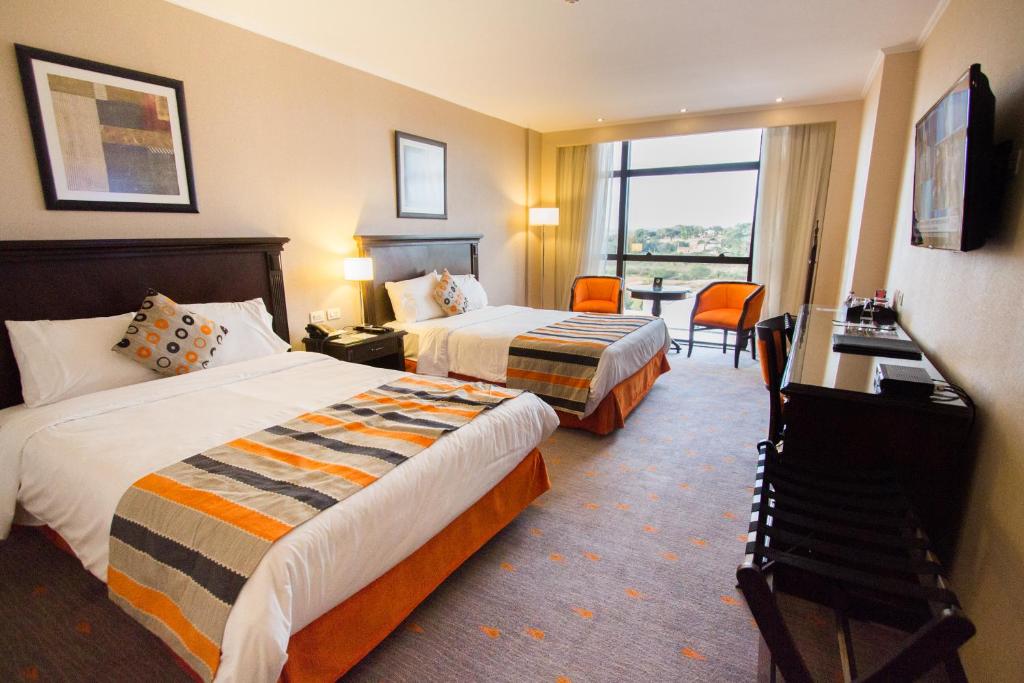 ein Hotelzimmer mit 2 Betten, einem Schreibtisch und einem Fenster in der Unterkunft Carnaval Hotel Casino in Encarnación
