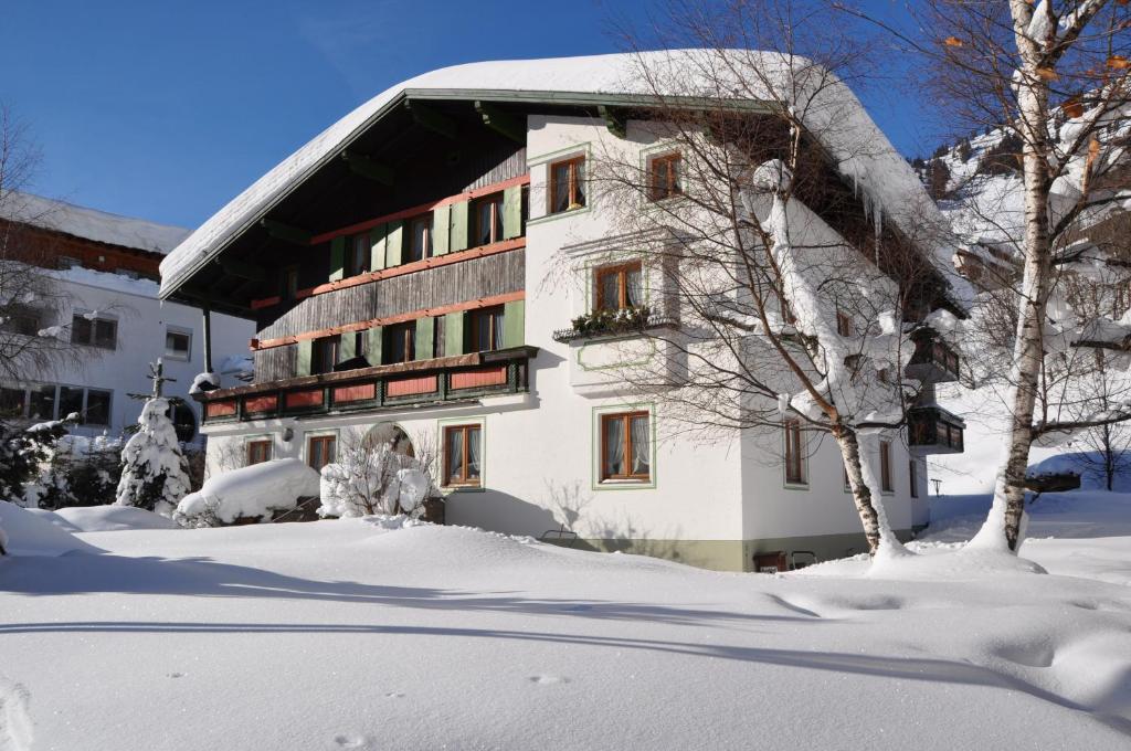 a building covered in snow with trees in front of it at Haus Gamberg in Sankt Anton am Arlberg