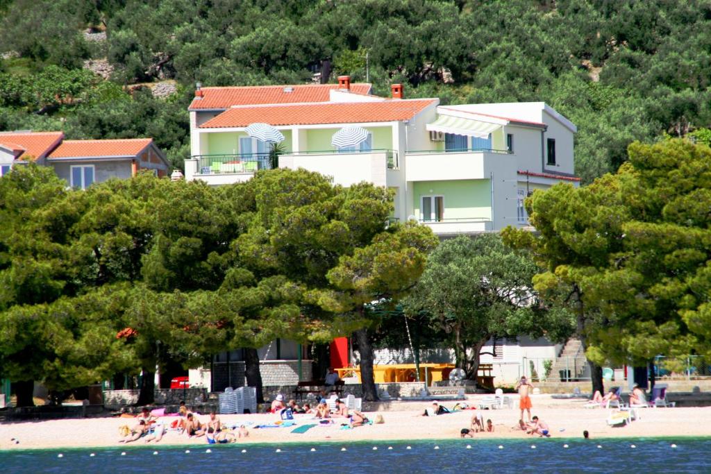 a group of people on a beach near a house at Rooms & Apartments Villa Anka in Tučepi