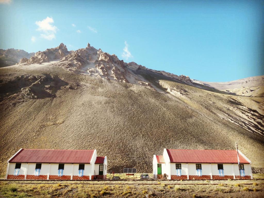 un edificio con techo rojo frente a una montaña en Hospedaje Leñas del Tolosa en Las Cuevas