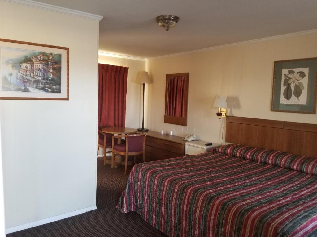 a hotel room with a bed and a table at Sooner Motel in Stroud
