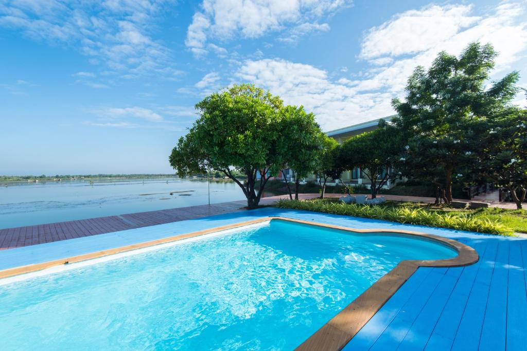 una piscina con agua azul y árboles en Baan Talay See Cream Resort, en Samut Songkhram