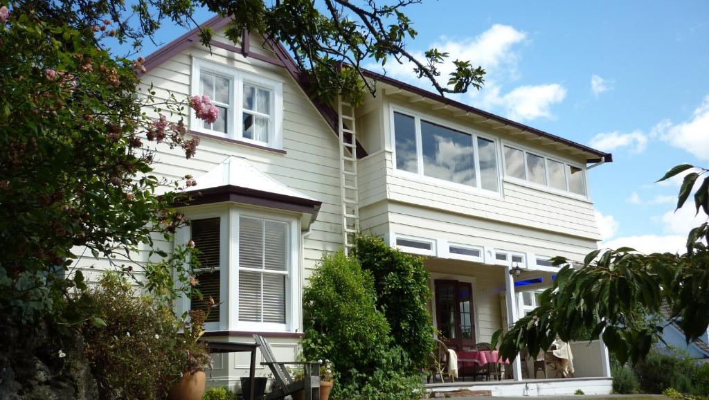 una casa con revestimiento blanco y ventanas en Cobden Garden, en Napier