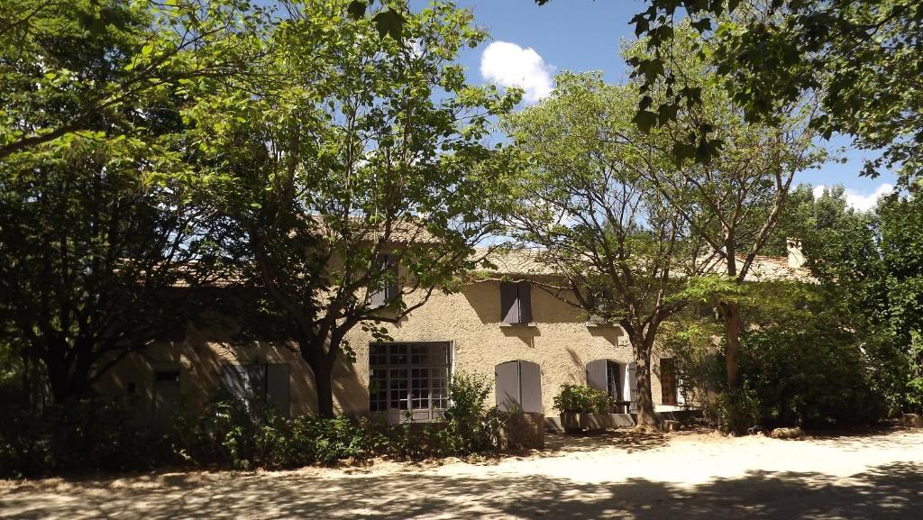 une maison blanche avec des arbres devant elle dans l'établissement Lou Jas d'Aimé, à Cavaillon