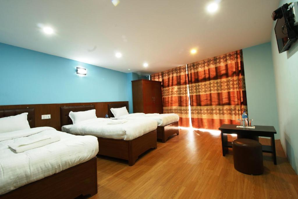 um quarto de hotel com três camas e uma janela em Everest Holiday Inn em Kathmandu