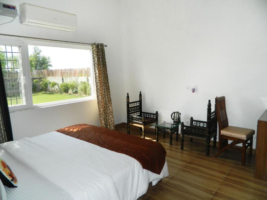 a bedroom with a bed and chairs and a window at Farmers Villa in Amritsar