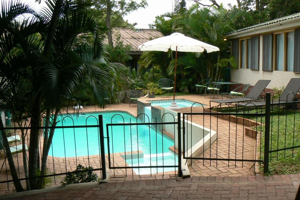a swimming pool with an umbrella next to a house at Fisheagle Accommodation in St Lucia
