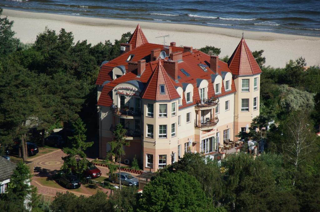 um grande edifício com um telhado vermelho na praia em Villa del Mar em Niechorze