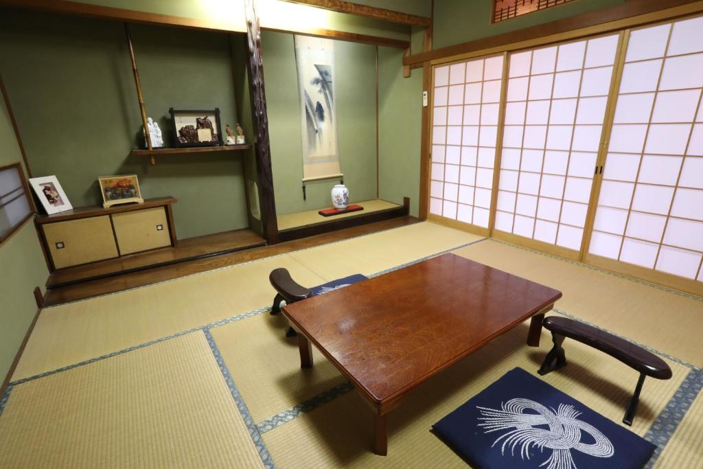 a room with a wooden table in a room with windows at Guesthouse Hikari in Kumano