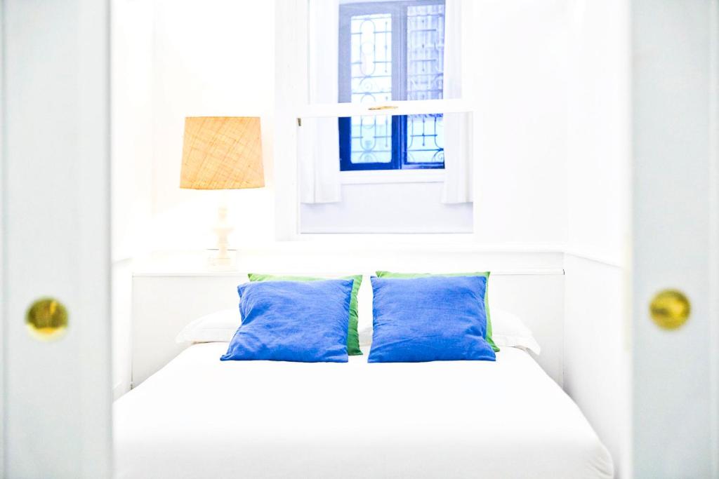 a white bed with blue pillows and a window at Prado Museum Boutique in Madrid