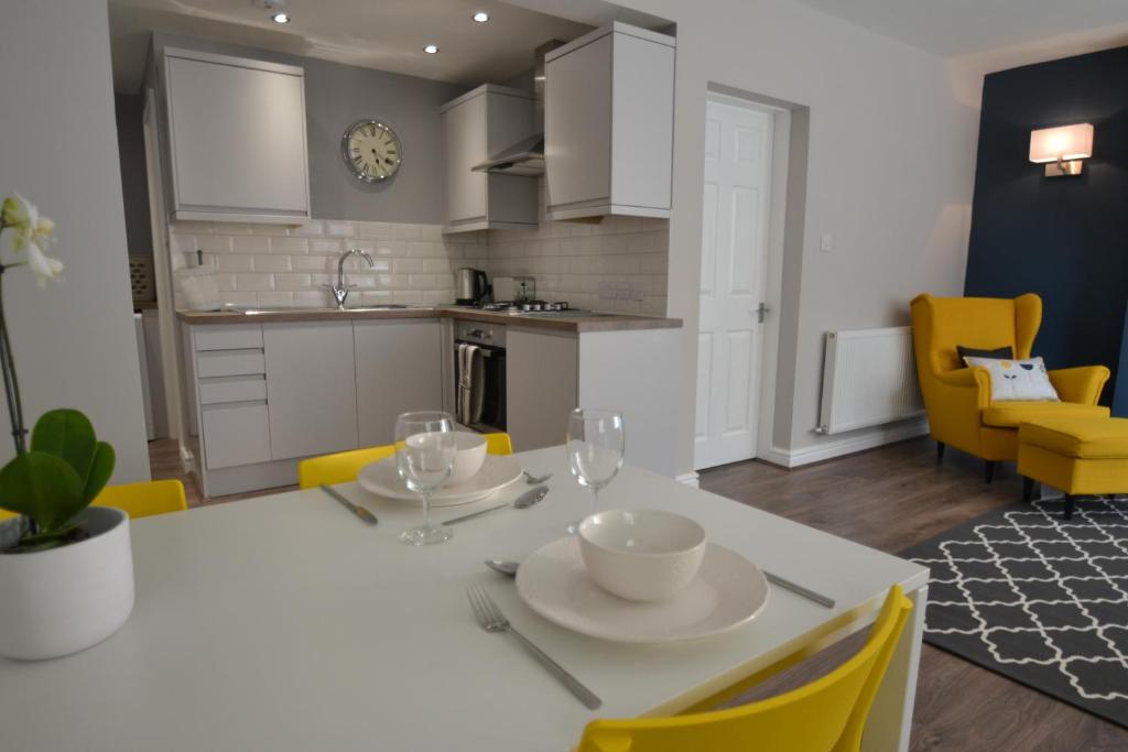 a kitchen and dining room with a white table and yellow chairs at Charming 1 bed riverside apartment in Chester