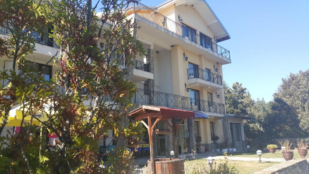 a white building with a balcony and a tree at Hotel Via Trayana in Beli Osŭm