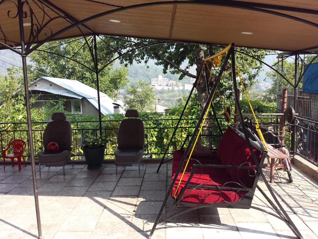 a porch with chairs and a swing on a patio at Bacho,s Cottage in Borjomi