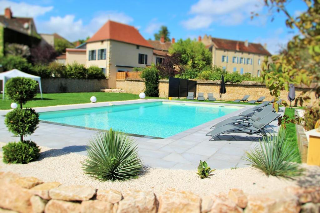 a swimming pool with lounge chairs and a house at Hôtel du Lion d'OR in Charolles