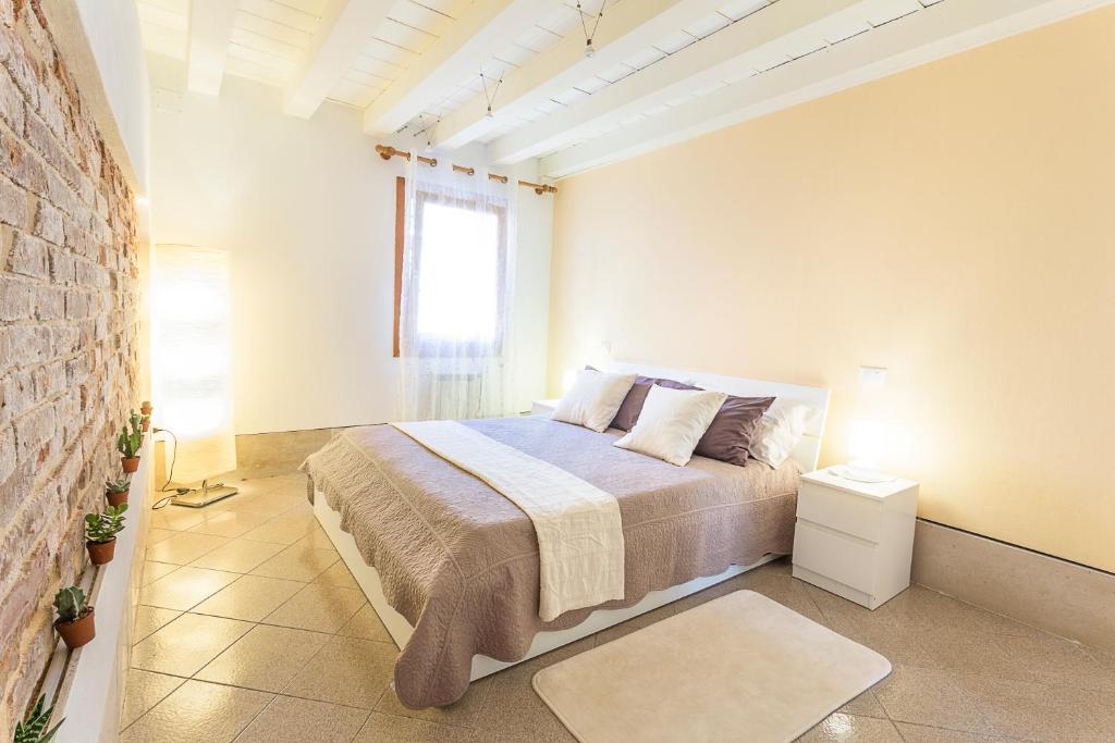 um quarto com uma cama e uma parede de tijolos em Cà Biennale, respirare la Venezia autentica! 0-27042-LOC-13975 Z07763 em Veneza