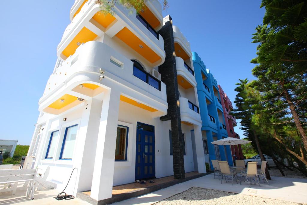 - un bâtiment bleu et blanc avec des chaises et un parasol dans l'établissement Easy Stay B&B, à Magong