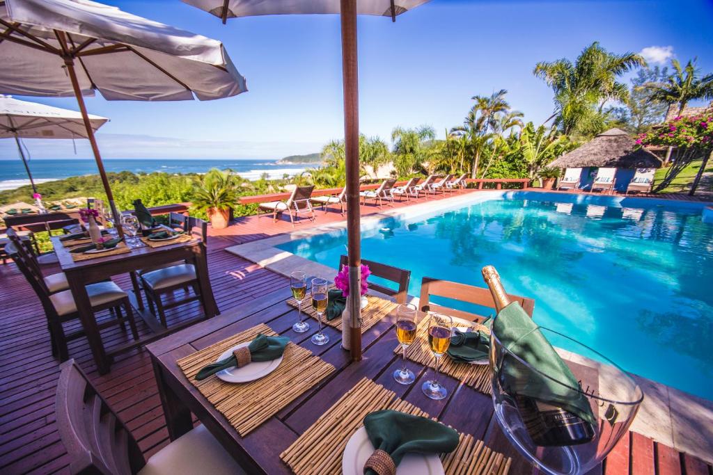 an outdoor dining area with a pool and tables and chairs at Vida Sol e Mar Ecoresort in Praia do Rosa
