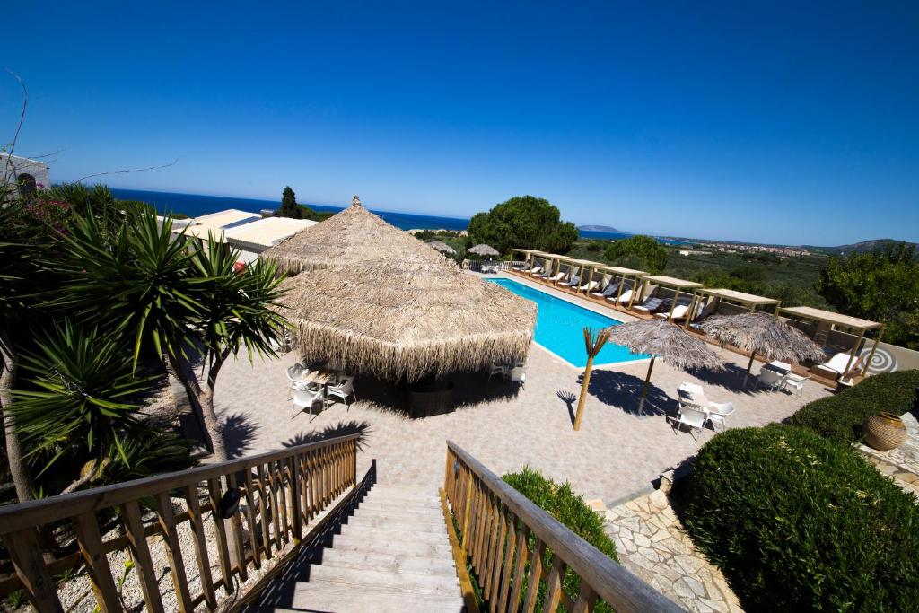 a resort with a swimming pool and a straw umbrella at Hotel Navarone in Petrochori