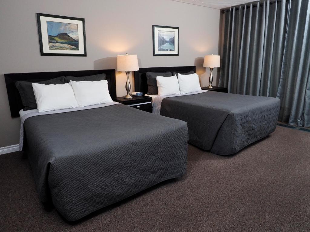 a hotel room with two beds and two lamps at Ambassador Motel in Sault Ste. Marie