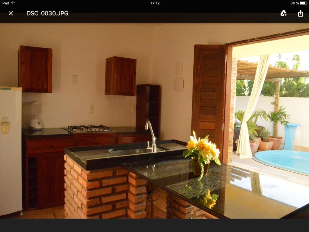 uma cozinha com um lavatório e uma cozinha com uma piscina em Pousada Casa do Bruno em Canoa Quebrada