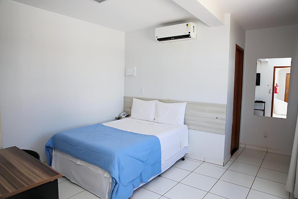 a white bedroom with a bed with a blue blanket at Bellonorte Hotel in Altamira
