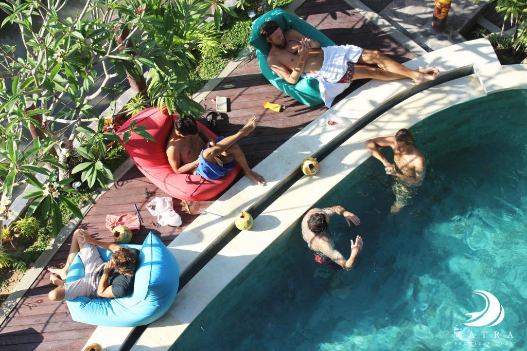 a group of people laying around a swimming pool at Matra Bali Surf Camp in Canggu