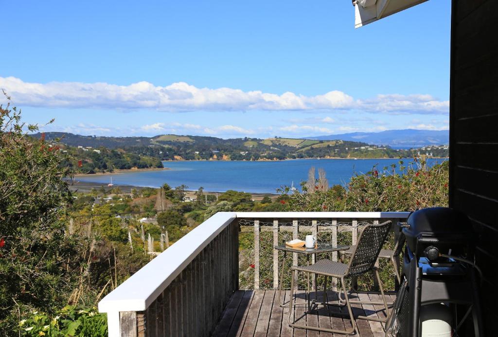 a balcony with a table and a view of a lake at Church Bay Views in Oneroa