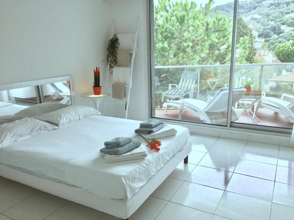 une chambre blanche avec un lit et un balcon dans l'établissement Appartements Cannes, à Cannes