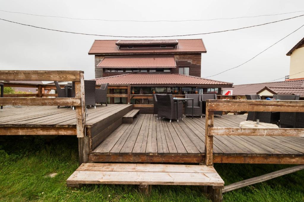una gran terraza de madera con sillas y un edificio en Restaurant Pensiunea Carmen, en Ranca