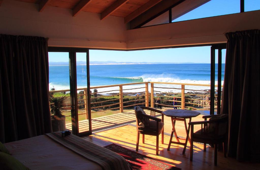 a bedroom with a balcony with a view of the ocean at Beach House in Jeffreys Bay