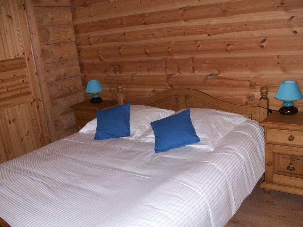 a bedroom with a white bed with blue pillows at Chambres d'hôtes la Ferme du Canard Argenté in Provenchères-sur-Fave