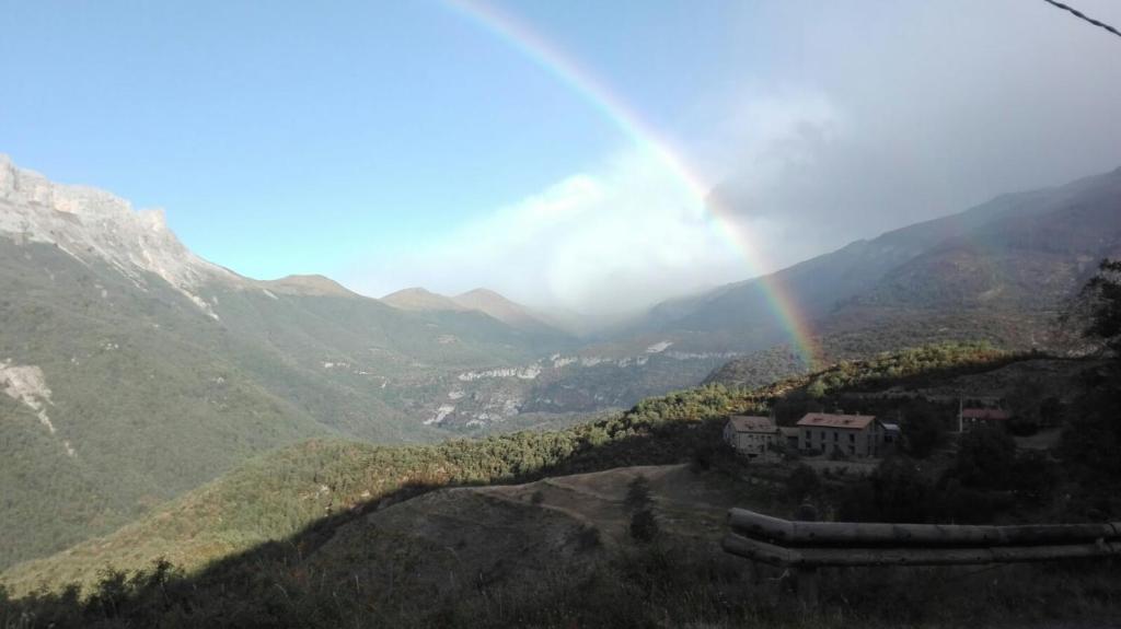 un arco iris sobre un valle con una casa en una colina en Hotel de Montaña Lamiana, en Lamiana
