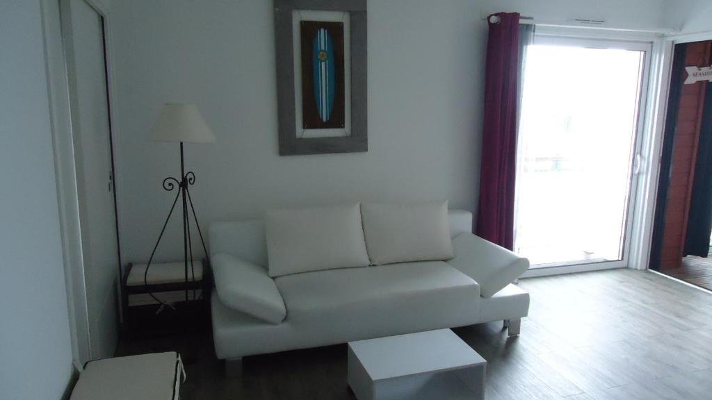 ein Wohnzimmer mit einem weißen Sofa und einem Fenster in der Unterkunft Le Neptune in Contis-les-Bains