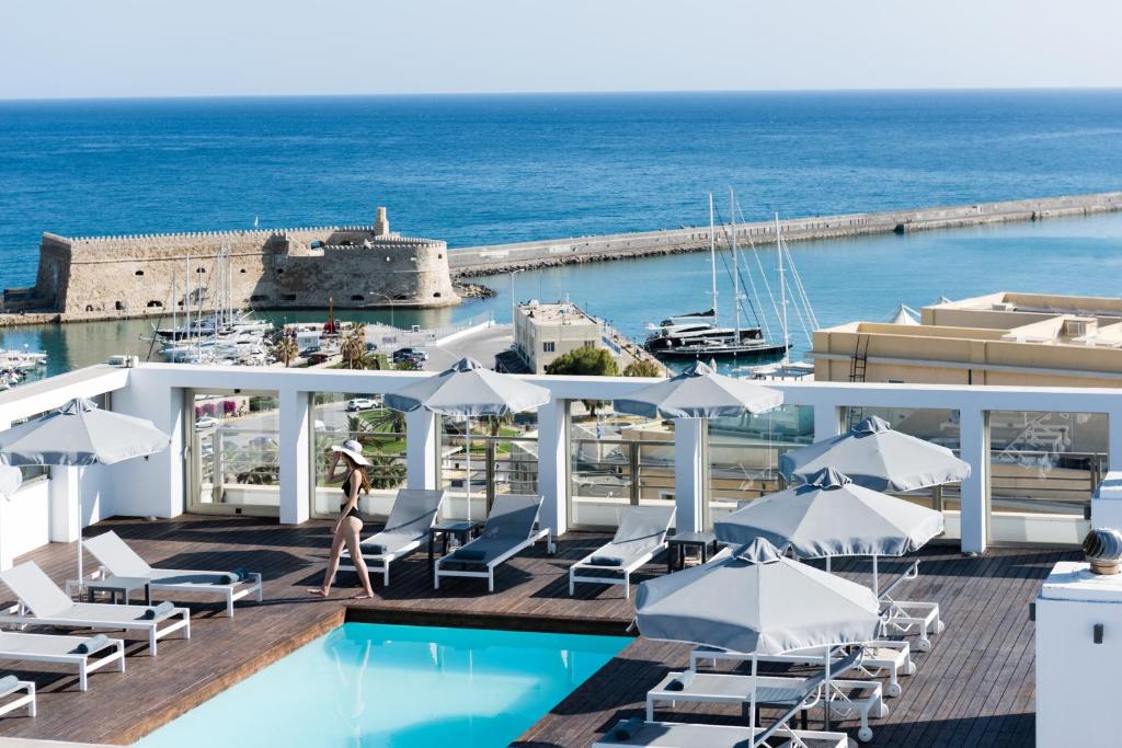 a beach area with a pool, chairs, and tables at Aquila Atlantis Hotel in Heraklio Town