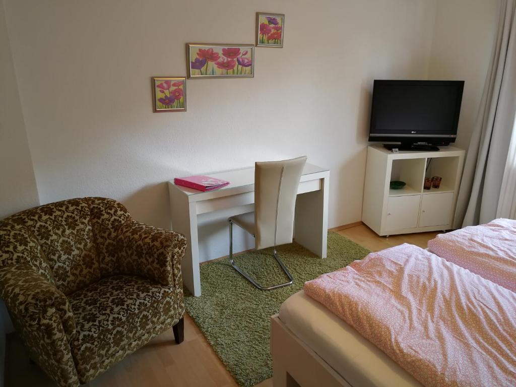 ein Schlafzimmer mit einem Schreibtisch, einem Stuhl und einem TV in der Unterkunft Köln Appartement in Köln