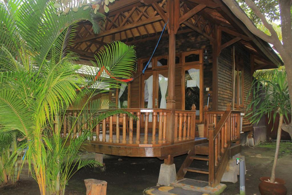 a wooden cabin with a porch in a forest at Bronze Bungalows in Gili Meno