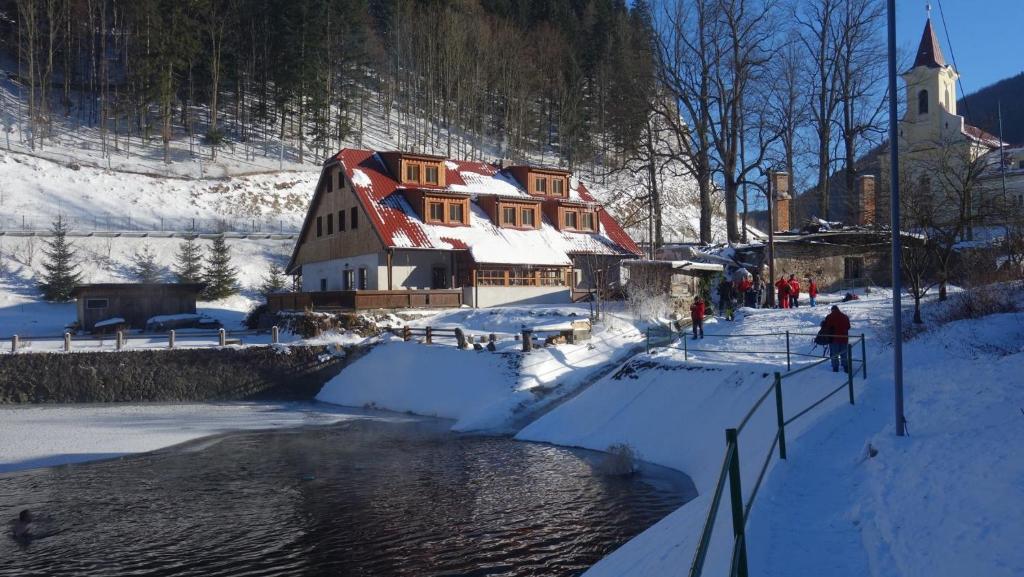 dom w śniegu obok rzeki w obiekcie Chata Motyčky w mieście Donovaly