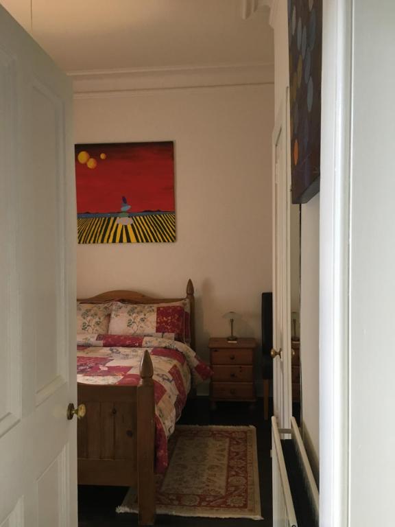a bedroom with a bed and a painting on the wall at Goldenacre Private Room (Homestay) in Edinburgh