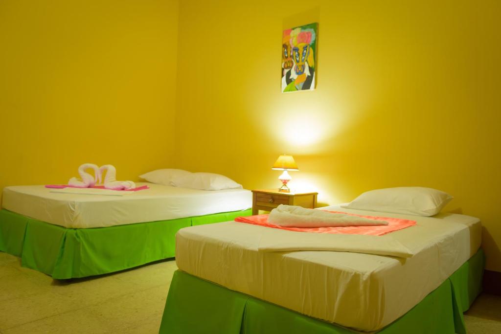 two beds in a room with yellow walls at Hostal Fachente in Le&oacute;n