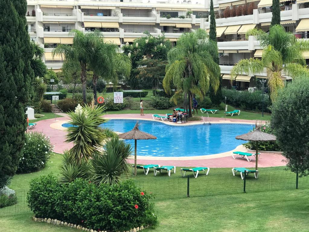 a swimming pool with chairs and umbrellas in a resort at Apartament Guadalmina in Marbella