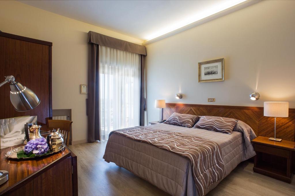 Hotel Cacciani في فراسكاتي: غرفة نوم بسرير وطاولة مع مصباح