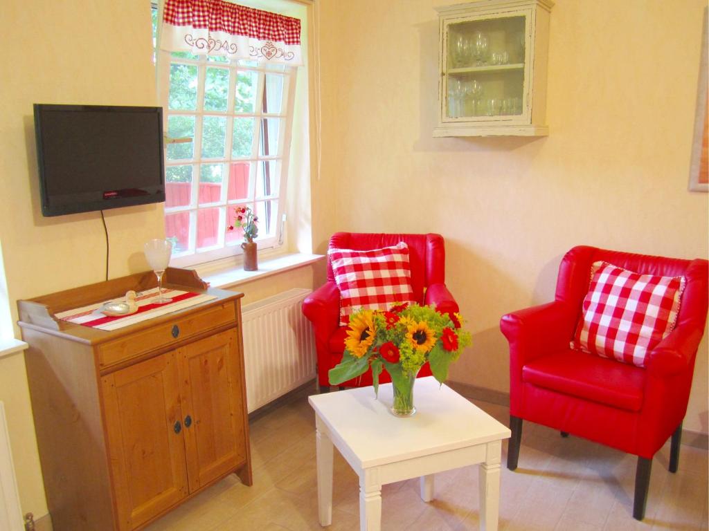 a living room with two red chairs and a vase of flowers at Apartment Am Mühlendeich in Vollerwiek