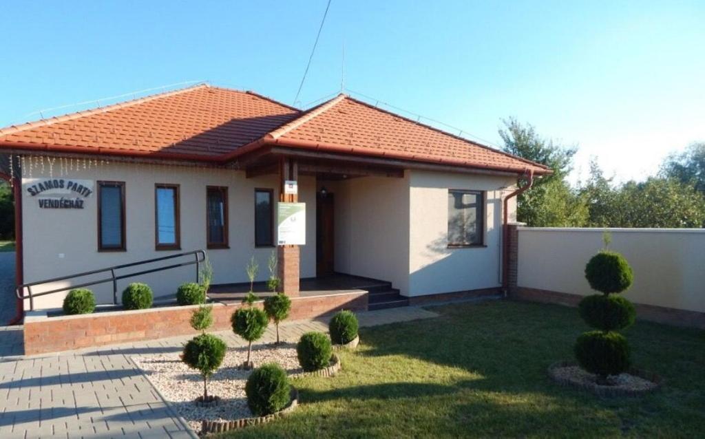 ein kleines weißes Haus mit einem Zaun und einem Hof in der Unterkunft Szamos-Party Vendégház in Olcsva
